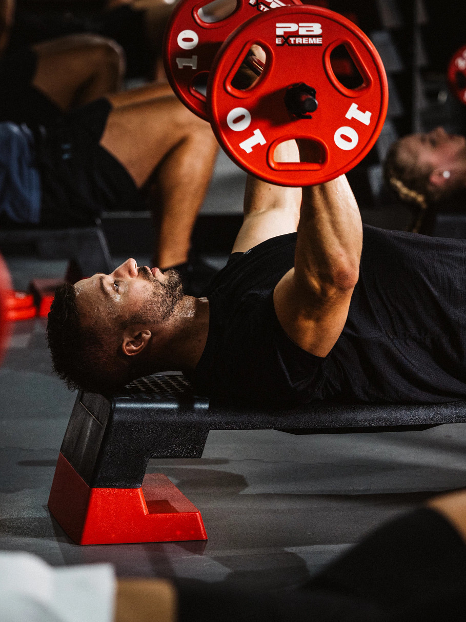 Mann beim Bankdrücken im Bodypump Kurs